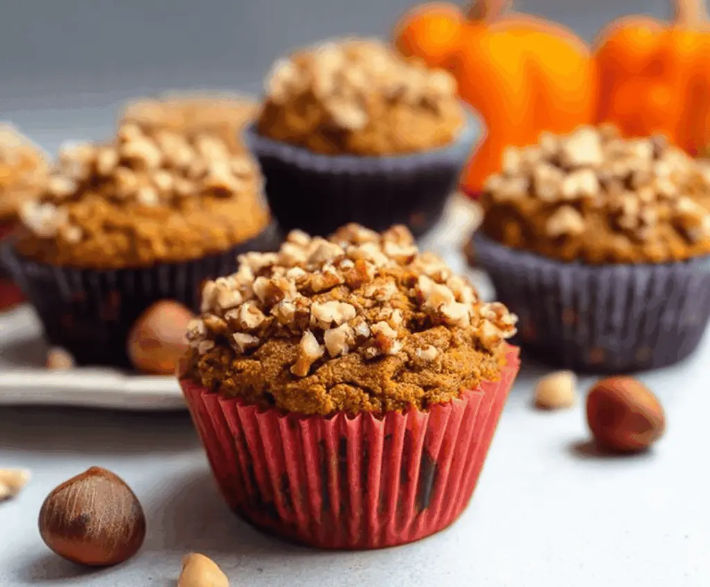 Delicious Pumpkin Hazelnut Muffins topped with chopped hazelnuts on a rustic wooden table