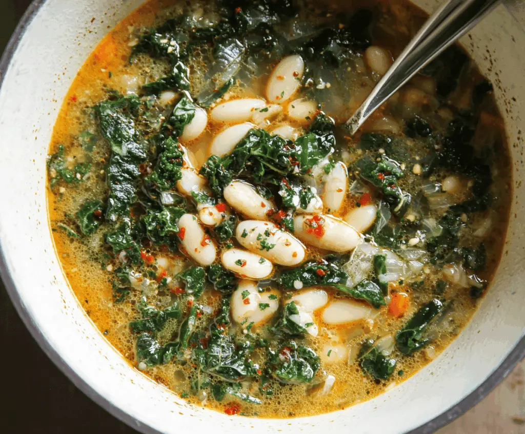 A steaming bowl of white bean and kale soup garnished with fresh herbs, showcasing a hearty and healthy meal perfect for cold days.