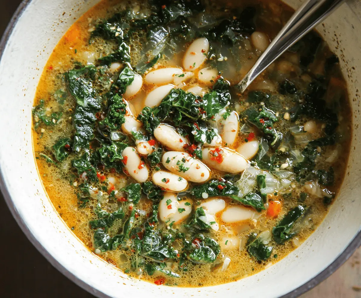 A steaming bowl of white bean and kale soup garnished with fresh herbs, showcasing a hearty and healthy meal perfect for cold days.