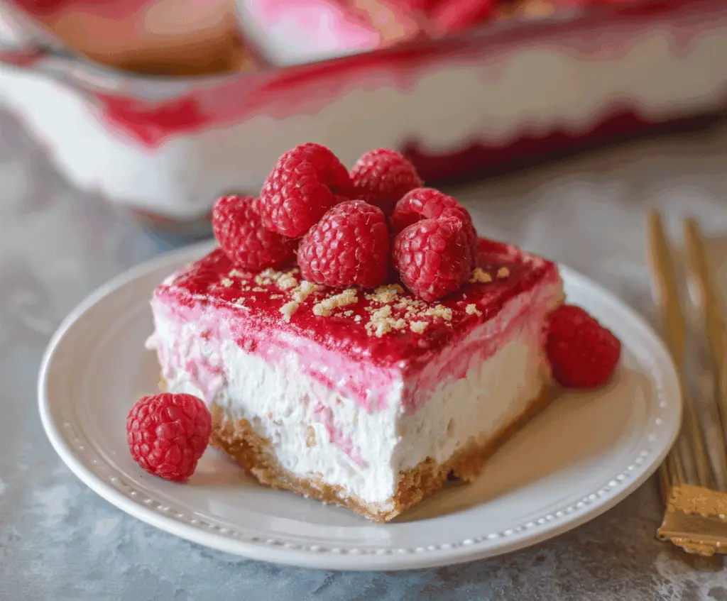 Delicious creamy raspberry pretzel dessert topped with fresh raspberries and whipped cream.