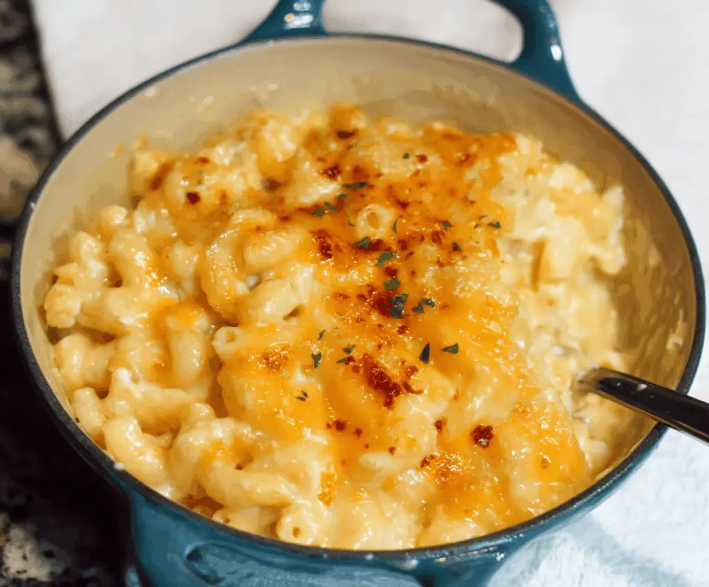 Creamy Paula Deen's Mac And Cheese served in a white bowl, featuring melted cheese and golden breadcrumbs topping.