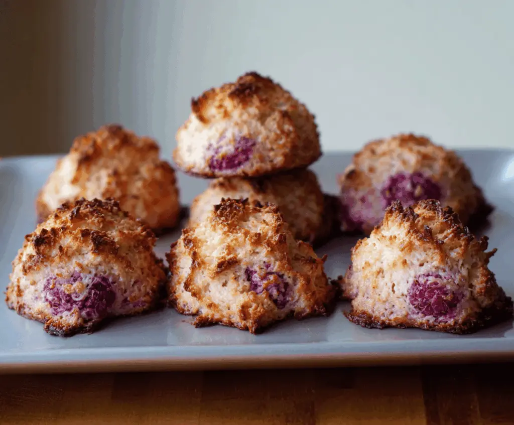 Delicious Raspberry Coconut Macaroons cookies on a white plate with fresh raspberries and shredded coconut.