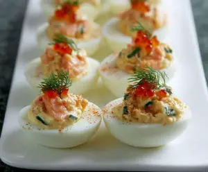 Delicious smoked salmon stuffed eggs garnished with fresh herbs on a white plate.