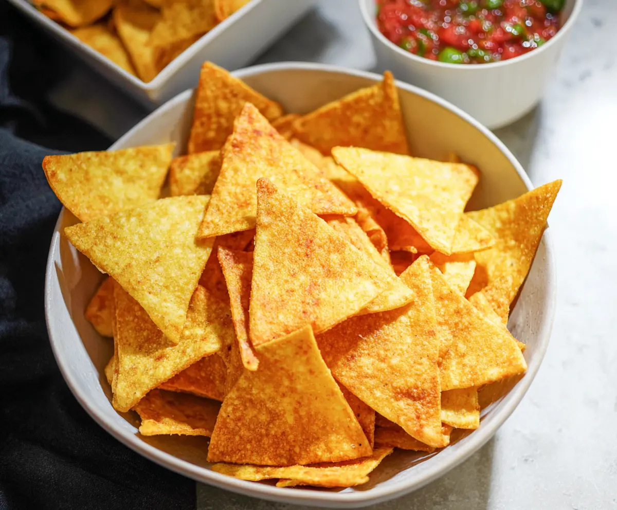 Crispy homemade tortilla chips served with salsa for a tasty snack.