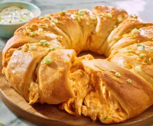 Delicious Buffalo Chicken Crescent Roll Ring topped with spicy buffalo sauce and melting cheese.