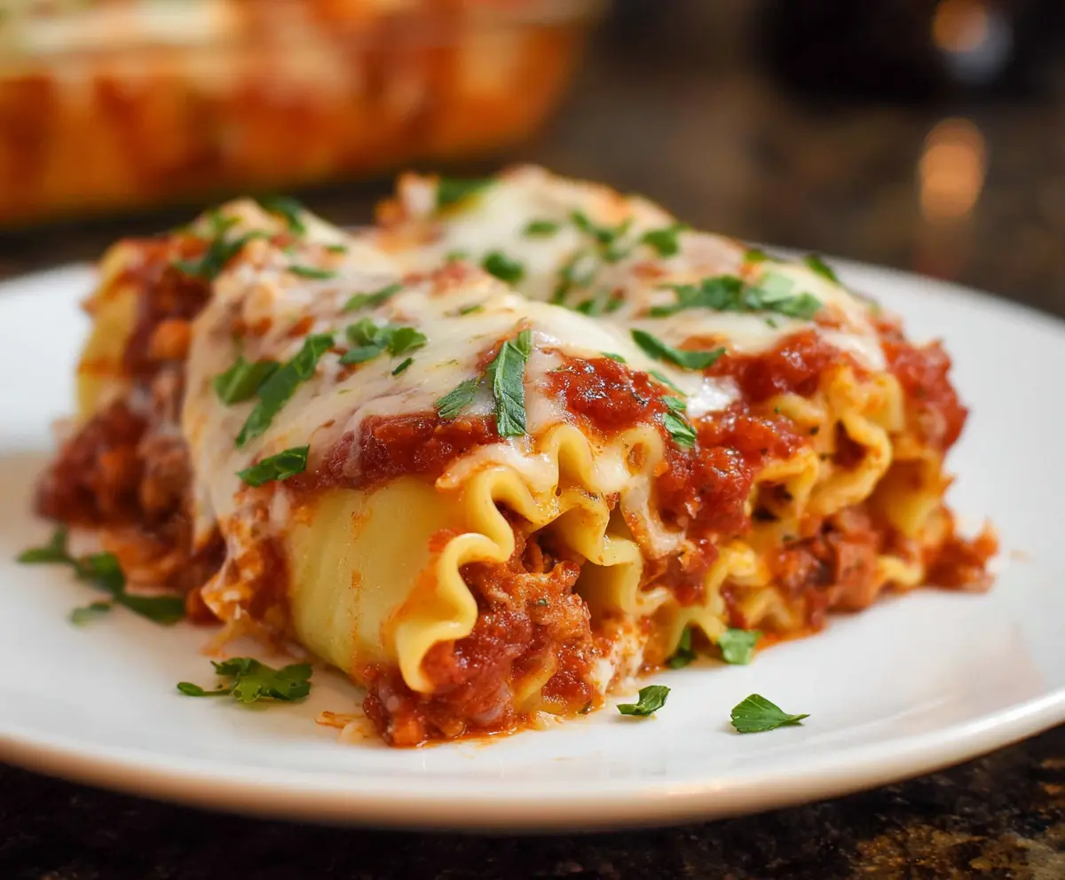 Cheesy lasagna roll-ups filled with rich meat sauce and creamy ricotta, served hot on a plate.