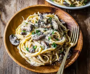 Creamy truffle mushroom pasta served in a white bowl, garnished with fresh herbs.