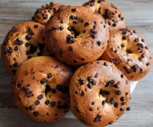 Delicious homemade chocolate chip bagels with a golden crust on a baking tray.