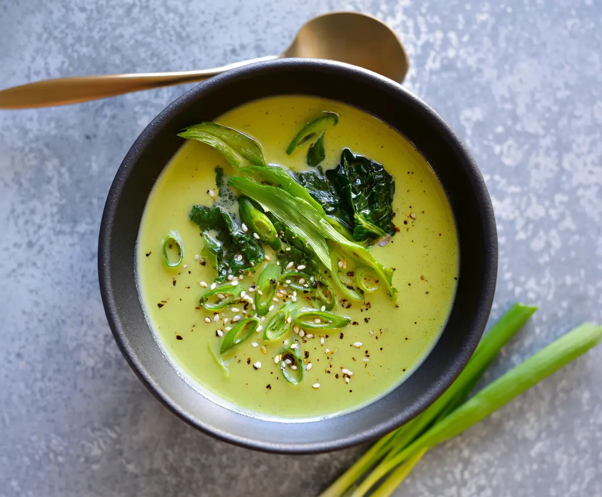 Creamy spring greens soup in a bowl garnished with fresh herbs, perfect for a healthy meal.