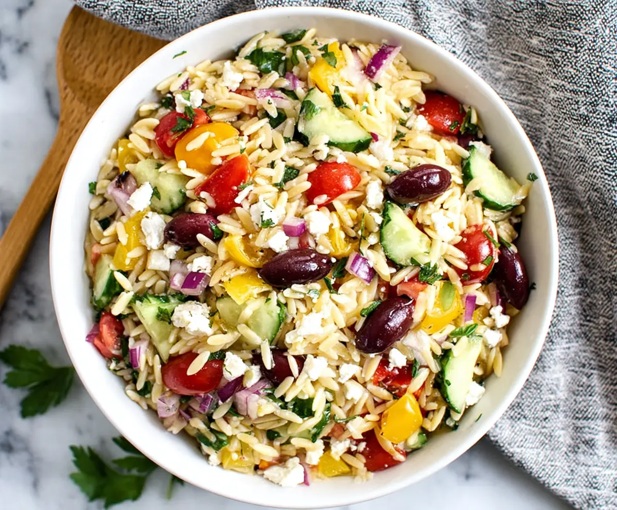 Fresh Greek orzo salad with cucumbers, tomatoes, feta cheese, and herbs in a vibrant bowl